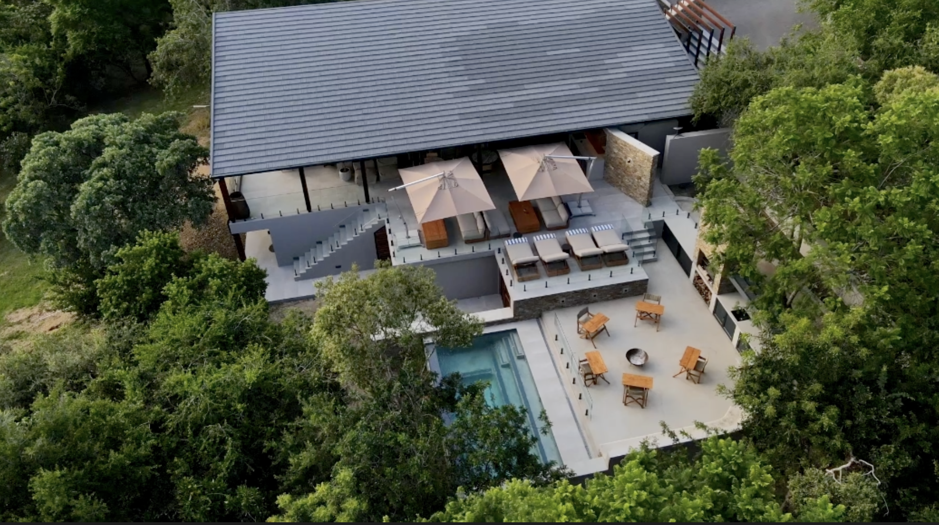 Aerial view of Grasslands Private Lodge, its terraces and pool surrounded by trees